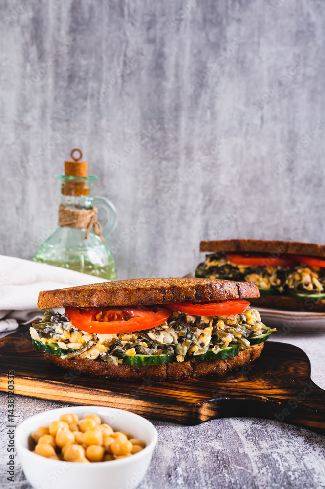 Vegetarian sandwich with seaweed, chickpeas, cucumber and tomato on grain bread vertical view