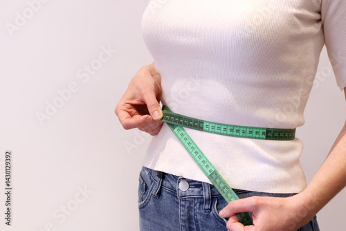 Obraz na płótnie Girl measures her waist with a tape measure. Girl with a tape measure in her hands. Concept of losing weight, diet and weight control. Body volume control. Girl measures her figure after losing weight w salonie