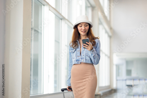 Obraz na płótnie Happy Female Travelling use smartphone. Happy asian woman passenger traveler waiting for departure with suitcase at modern airport terminal w salonie