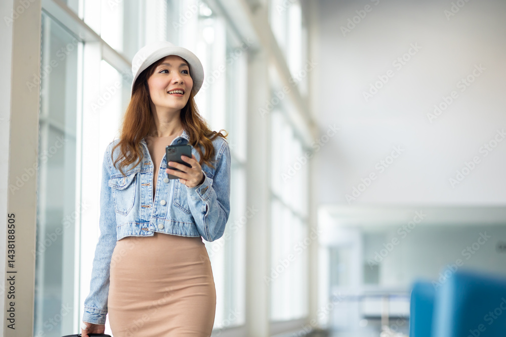 Happy Female Travelling use smartphone. Happy asian woman passenger traveler waiting for departure with suitcase at modern airport terminal