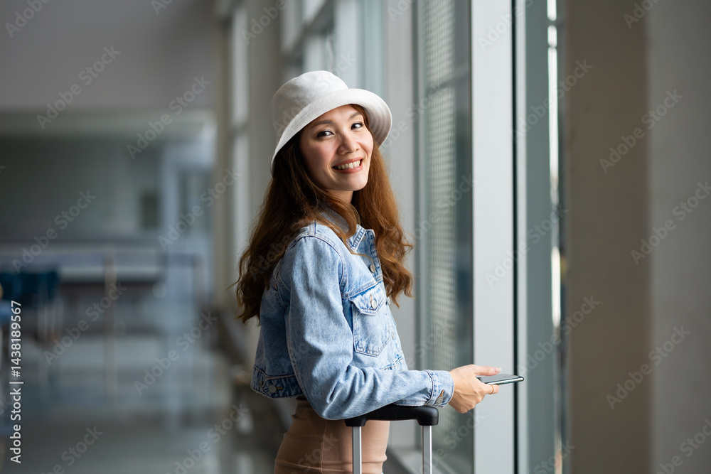 Portrait Happy Asian Female traveler passenger with luggage. Happy Asian beautiful woman passenger traveler waiting for departure with suitcase at modern airport terminal