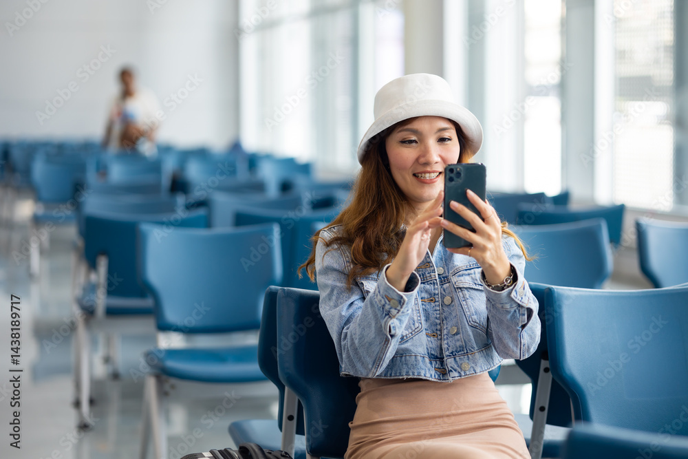Waiting to board a plane at the airport. Asian Woman waiting for flight at airport lounge. Happy asian woman passenger traveler waiting for departure with suitcase at modern airport terminal