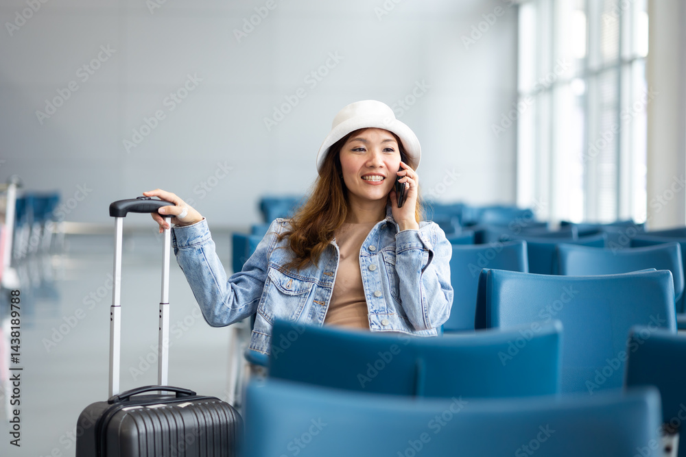 Waiting to board a plane at the airport. Asian Woman waiting for flight at airport lounge. Happy asian woman passenger traveler waiting for departure with suitcase at modern airport terminal