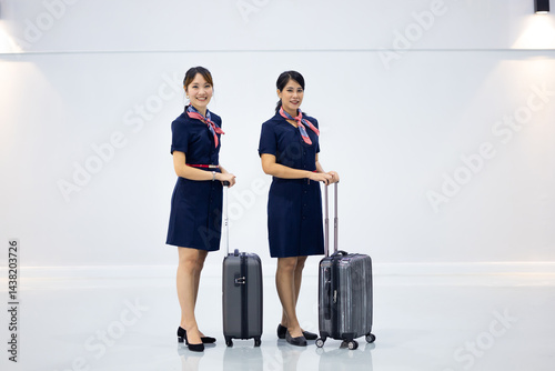 Portrait two Cabin crew or air hostess in airport. Cabin crew, air hostess working in airplane. Service mind. Asian stewardess with suitcase at modern airport terminal. flight attendant