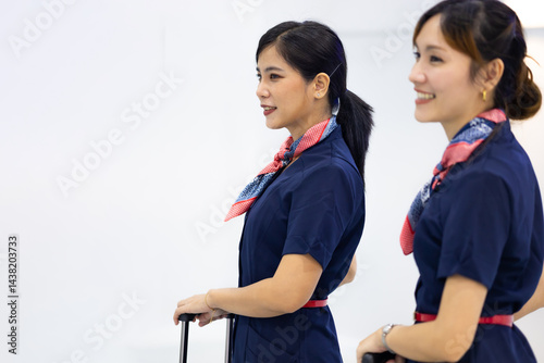 Portrait two Cabin crew or air hostess in airport. Cabin crew, air hostess working in airplane. Service mind. Asian stewardess with suitcase at modern airport terminal. flight attendant