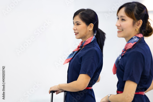Portrait two Cabin crew or air hostess in airport. Cabin crew, air hostess working in airplane. Service mind. Asian stewardess with suitcase at modern airport terminal. flight attendant