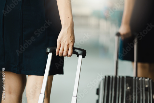 Obraz na płótnie Closeup hand woman Walking in airport. Cabin crew, air hostess working in airplane. Service mind. Asian stewardess with suitcase at modern airport terminal. flight attendant w salonie