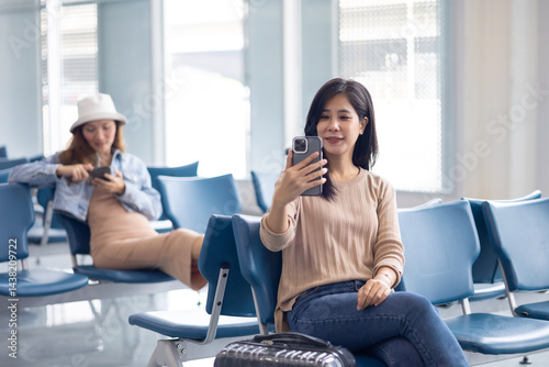 Obraz na płótnie Happy Asian Woman waiting for flight at airport lounge. Happy asian woman passenger traveler waiting for departure with suitcase at modern airport terminal w salonie