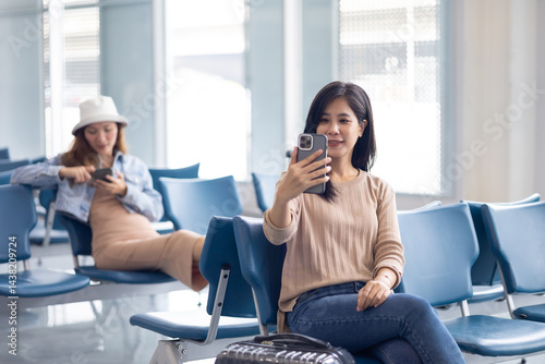 Obraz na płótnie Happy Asian Woman waiting for flight at airport lounge. Happy asian woman passenger traveler waiting for departure with suitcase at modern airport terminal w salonie