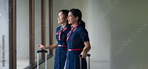 Obraz na płótnie Portrait two Cabin crew or air hostess in airport. Cabin crew, air hostess working in airplane. Service mind. Asian stewardess with suitcase at modern airport terminal. flight attendant w salonie