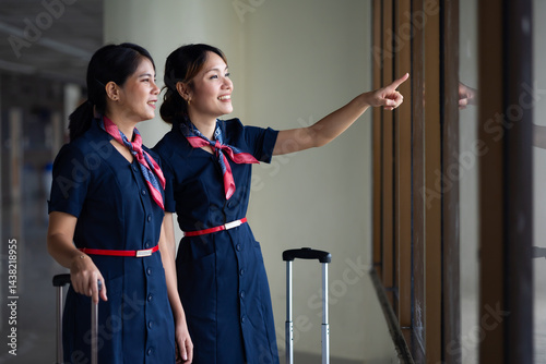 Obraz na płótnie Portrait two Cabin crew or air hostess in airport. Cabin crew, air hostess working in airplane. Service mind. Asian stewardess with suitcase at modern airport terminal. flight attendant w salonie