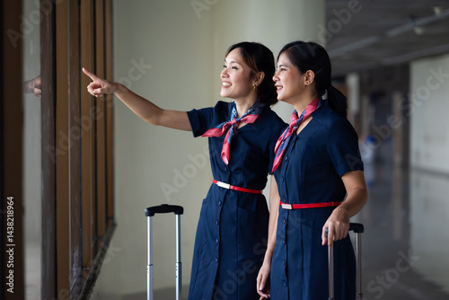 Obraz na płótnie Portrait two Cabin crew or air hostess in airport. Cabin crew, air hostess working in airplane. Service mind. Asian stewardess with suitcase at modern airport terminal. flight attendant w salonie