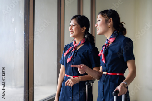 Portrait two Cabin crew or air hostess in airport. Cabin crew, air hostess working in airplane. Service mind. Asian stewardess with suitcase at modern airport terminal. flight attendant