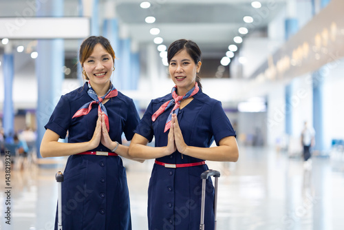 Obraz na płótnie Portrait two woman friends sawasdee thai hello in airport. Cabin crew, air hostess working in airplane. Service mind. Asian stewardess with suitcase at modern airport terminal. flight attendant w salonie
