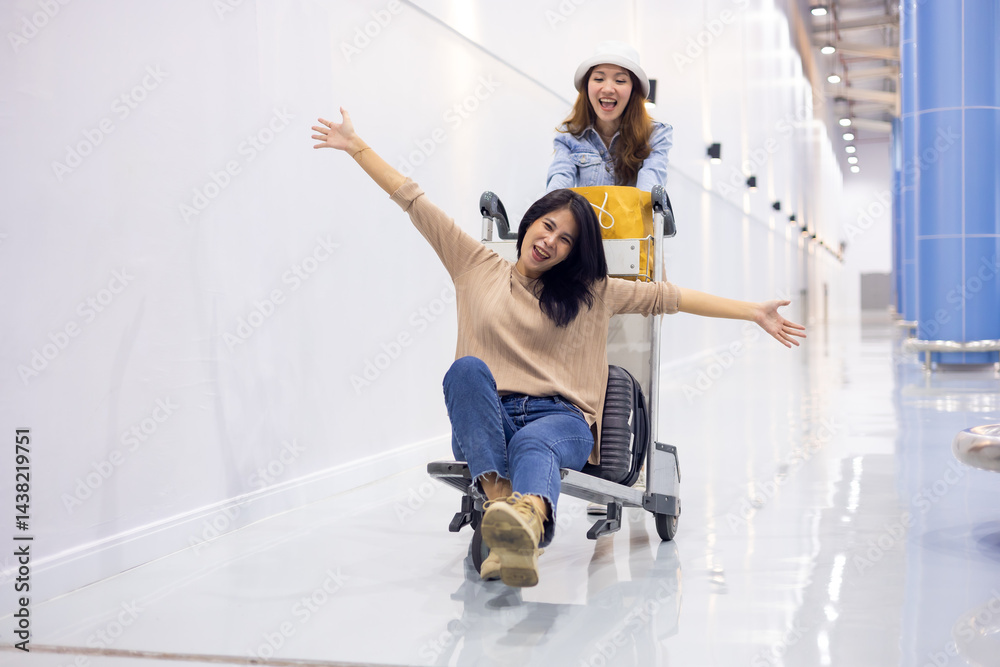 Riding baggage trolley. two Happy Asian beautiful woman passenger traveler and friends having fun with luggage at the airport