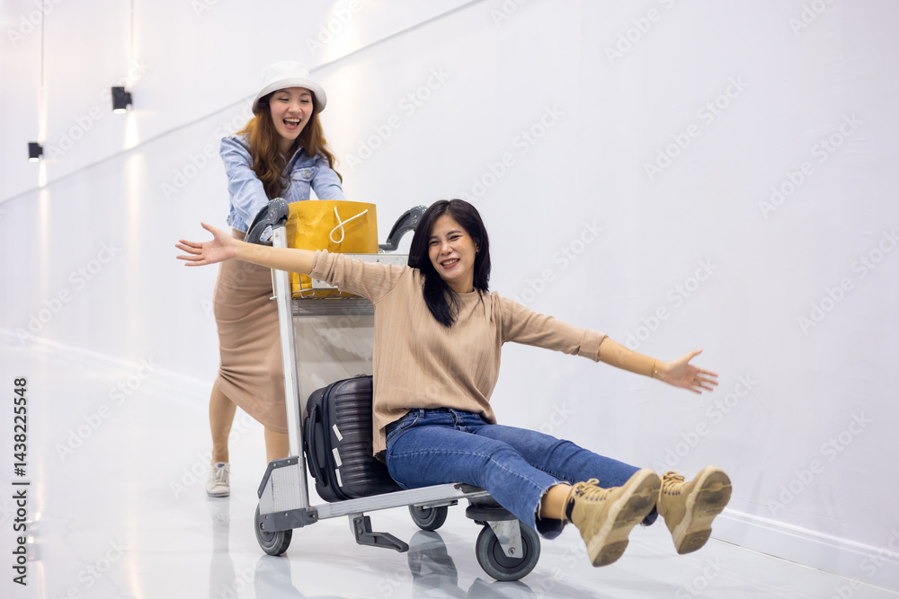 Riding baggage trolley. two Happy Asian beautiful woman passenger traveler and friends having fun with luggage at the airport