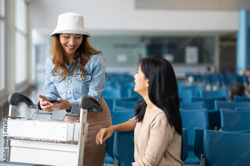 Two Asian Woman waiting for flight at airport lounge. Happy asian woman passenger traveler waiting for departure with suitcase at modern airport terminal