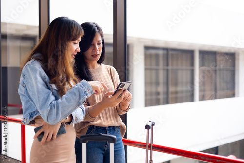 Obraz na płótnie Two Asian Woman waiting for flight at airport lounge. Happy asian woman passenger traveler waiting for departure with suitcase at modern airport terminal w salonie