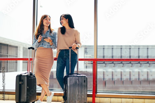 Obraz na płótnie Two Asian Woman waiting for flight at airport lounge. Happy asian woman passenger traveler waiting for departure with suitcase at modern airport terminal w salonie