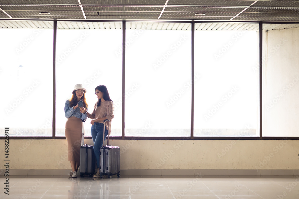 Two Asian Woman waiting for flight at airport lounge. Happy asian woman passenger traveler waiting for departure with suitcase at modern airport terminal