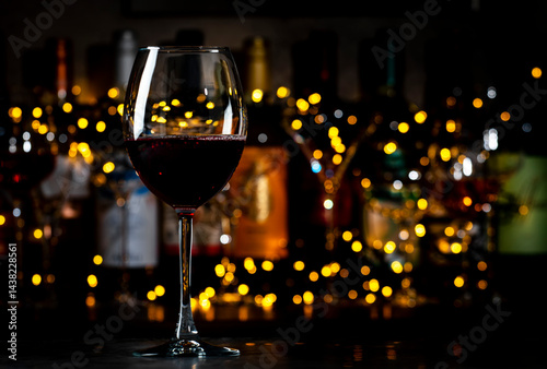 Italian dry red wine sangiovese in glass and wine bottles on dark bar background with lights