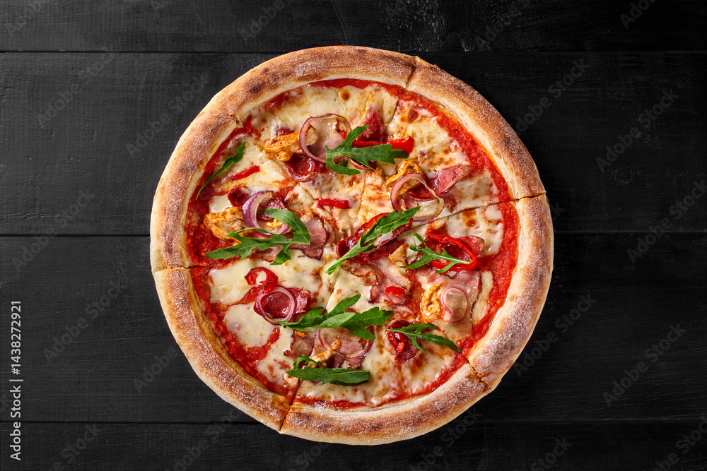 Delicious pizza with chicken, bacon, arugula, and mozzarella on black wooden table