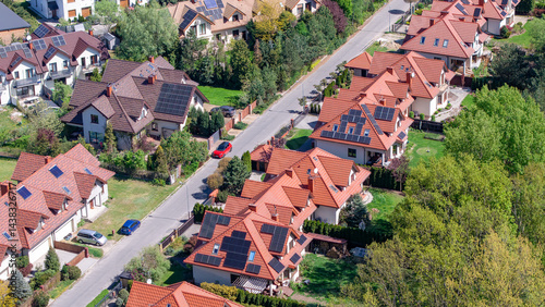 Tableau sur toile Aerial view of suburban houses in a green environment near a large metropolis, featuring modern single-family homes equipped with solar panels on their roofs
