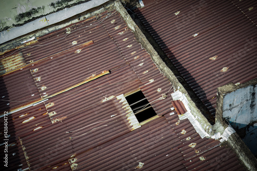 Rusty corrugated metal roof with a hole and worn edges