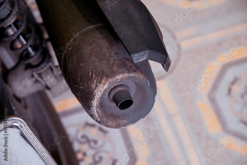 Close-up of an old motorcycle exhaust pipe with rust and scratches