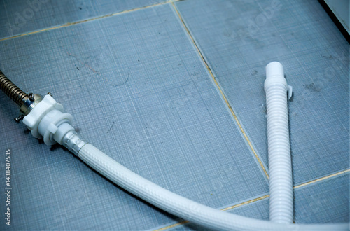 White Plastic Plumbing Pipes and Connectors on Blue Tile Floor