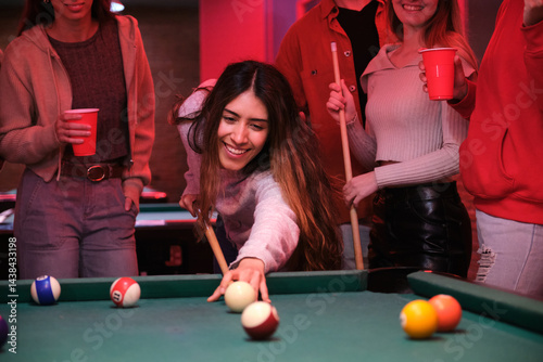 Group of friends having fun playing pool and drinking in a nightclub