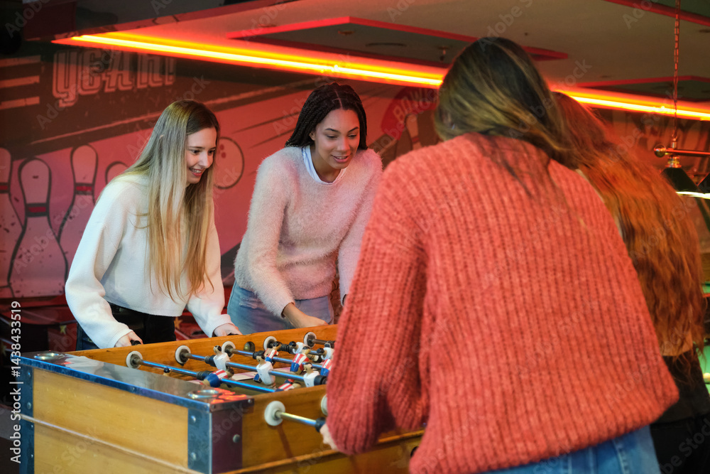 Group of friends having fun playing foosball in a colorful bowling center