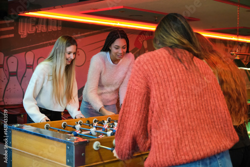 Obraz na płótnie Group of friends having fun playing foosball in a colorful bowling center w salonie