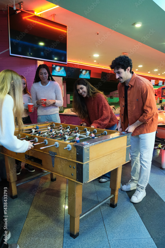 Friends playing foosball and having fun together in a game room