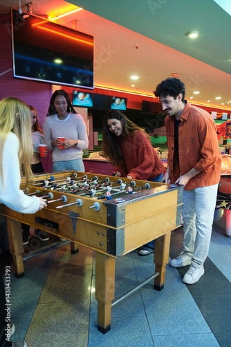 Obraz na płótnie Friends playing foosball and having fun together in a game room w salonie