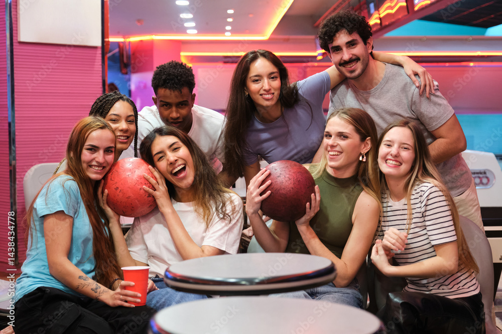 Group of happy friends holding bowling balls, having fun and enjoying their time together at the bowling alley