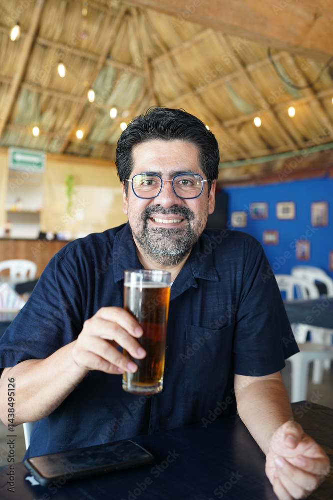Smiling hispanic man enjoying a refreshing beer at a caribbean bar Smiling hispanic man enjoying a refreshing beer at a caribbean bar