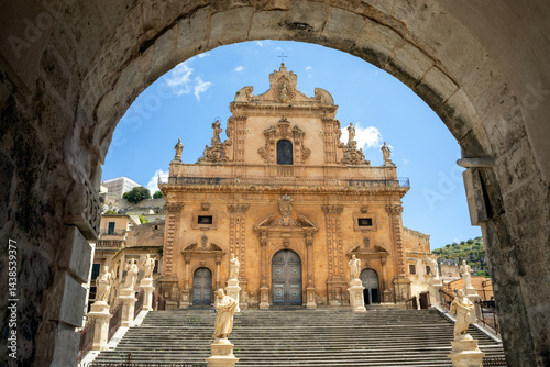 Facade of the Cathedral of St. Peter the Apostle in Modica, Sicily, Italy, with its typical staircase seen from an arch