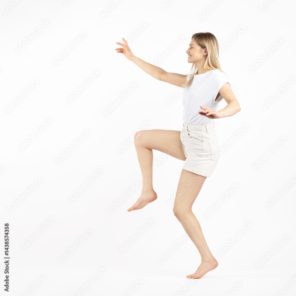 Studio portrait of beautiful young woman with one leg raised and happy facial expression. White studio background with copy space Studio portrait of beautiful young woman with one leg raised and happy facial expression. White studio background with copy space