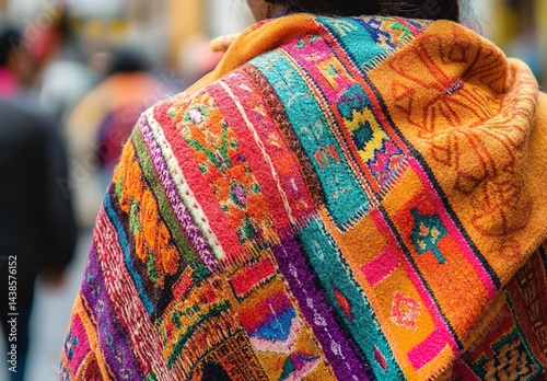 Person's back wearing vibrant traditional-patterned shawl in crowded area.