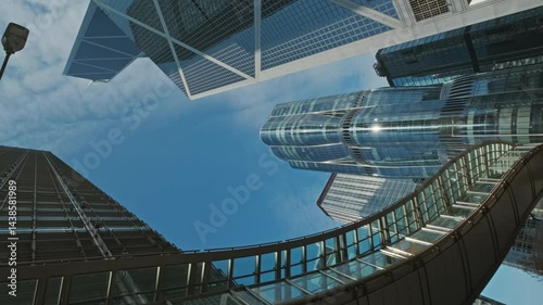 Tall glass skyscrapers rise against a blue sky, modern architecture in urban area, Hong Kong, 4k