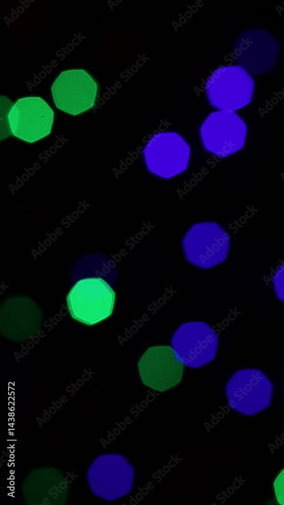 Una toma de cerca de varias luces de colores en forma de círculos en movimiento en la oscuridad. Desenfoque, efecto Bokeh. Video vertical