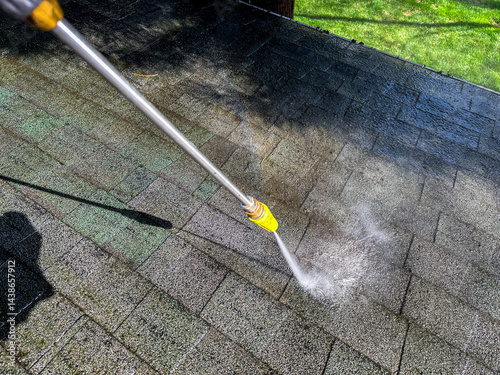Cleaning a roof with a pressure washer on a sunny day in a backyard