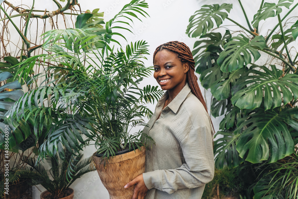 A woman gracefully poses with a bright houseplant surrounded by beautiful lush greenery