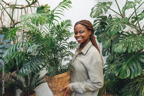 Obraz na płótnie A woman gracefully poses with a bright houseplant surrounded by beautiful lush greenery w salonie