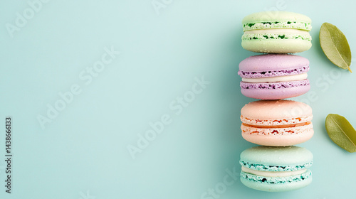   A stack of macaroons perched atop a green leaf against a blue backdrop