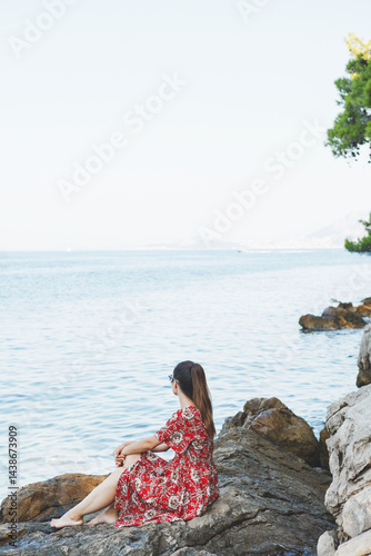 A Serene Girl at a Beautiful Seaside Enjoying Relaxation on the Rocks by the Ocean