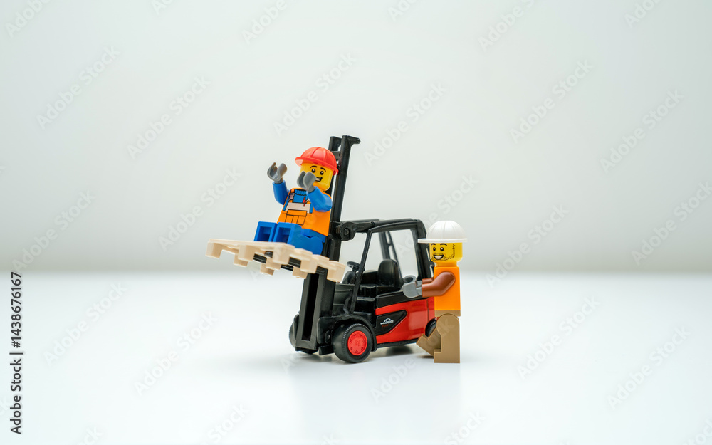 Obraz premium Tallinn, Harju, Estonia - 12.03.2023: Dangerous construction scene with LEGO workers, one sits unsafely on on a white background. One operates the forklift, the other sits smiling on a lifted pallet.