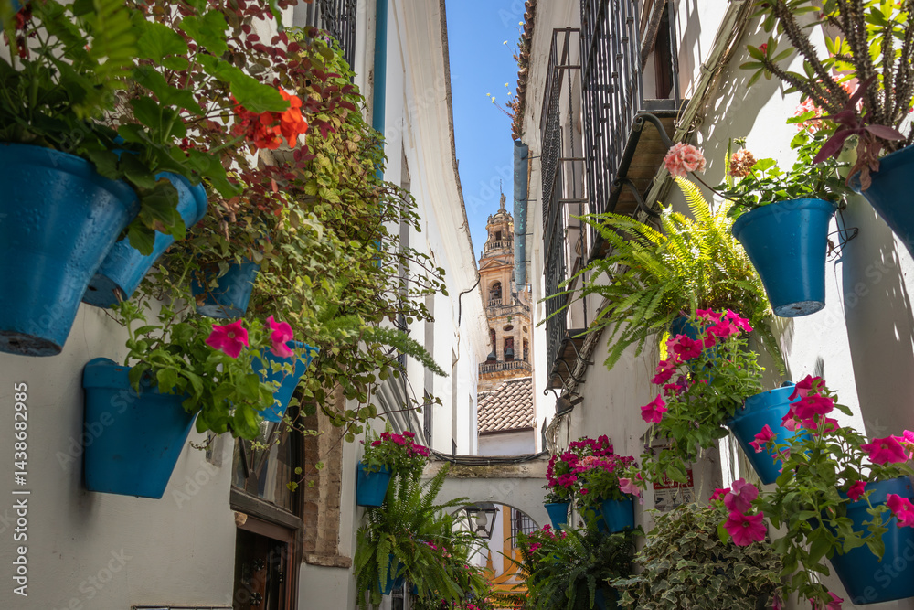 Fototapeta premium Calleja de las Flores in Córdoba. Beautiful Tourist Narrow Street with Flowers in Pots and Mosque–Cathedral of Córdoba in the Background in Andalusian Spain.