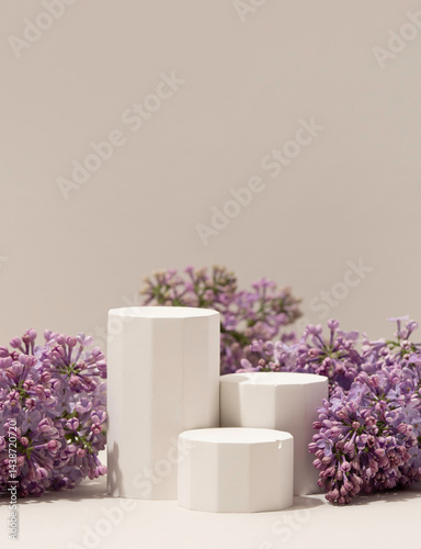 Obraz na płótnie Elegant minimalistic spring-themed product display with white geometric pedestals surrounded by fresh lilac flowers on soft neutral background. Vertical photography. w salonie